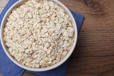 Bowl with oatmeal on wooden table, top view. Space for text