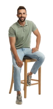 Beyaz arka planda taburede oturan yakışıklı adam.