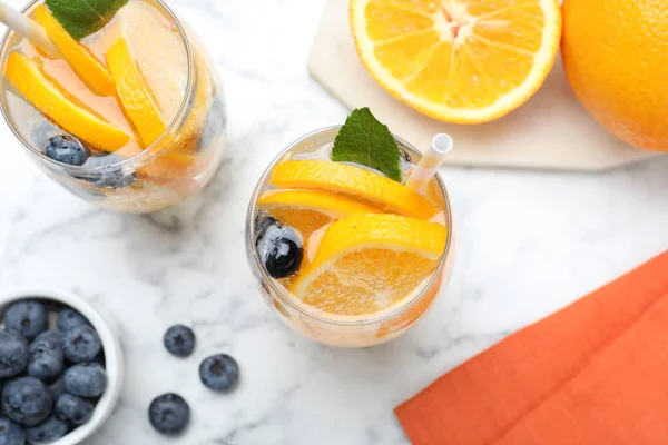 白い大理石のテーブルの上にソーダ水 ミントとブルーベリーとおいしいオレンジレモネードのフラットレイアウト組成 新鮮な夏のカクテル — ストック写真