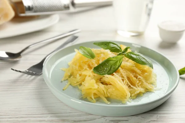 Tasty spaghetti squash with basil and cheese served on white wooden table, closeup