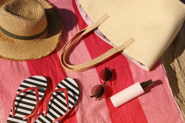 Straw hat, bag and other beach items on sandy seashore, closeup. View from above