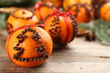 Pomander balls made of fresh tangerines with cloves  on wooden table, closeup. Space for text