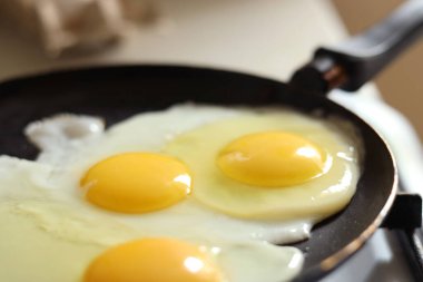 Cooking tasty eggs on frying pan, closeup