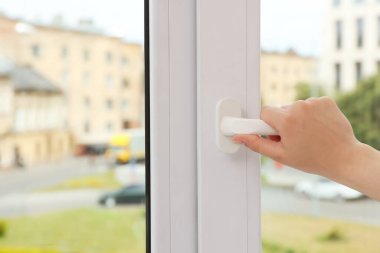 Woman opening white plastic window at home, closeup