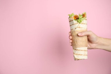 Woman holding delicious chicken shawarma on pink background, closeup. Space for text