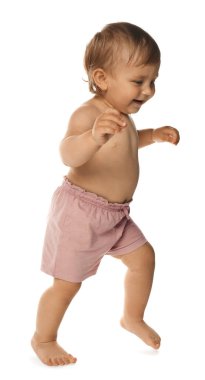 Cute baby in shorts learning to walk on white background
