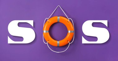 SOS message made from lifebuoy and white letters on violet background