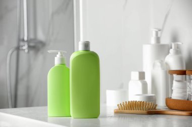 Shampoo, conditioner, other toiletries and wooden hairbrush on bathroom counter