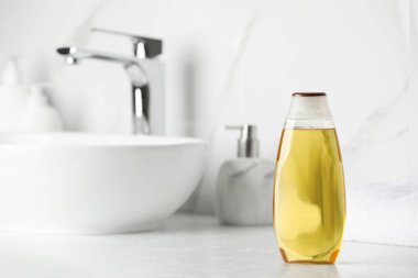 Bottle of shampoo near sink on bathroom counter, space for text