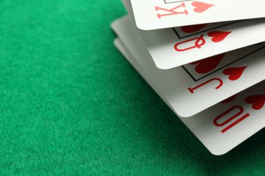 Hand of playing cards on green table, closeup. Space for text