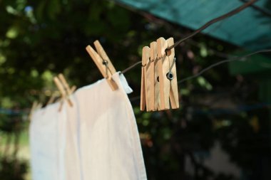 Washing line with clean laundry and clothespins outdoors, closeup