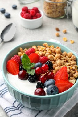 Bowl with tasty granola and berries on light grey table. Healthy meal