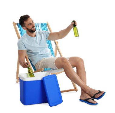 Happy man with bottles of beer near cool box on white background