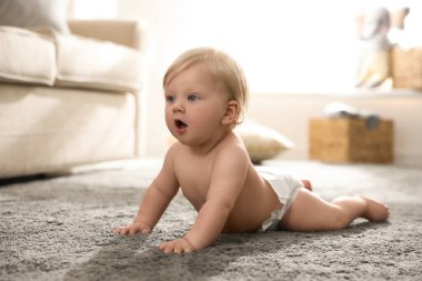Evdeki halının üstünde bebek bezi takmış şirin bir bebek.