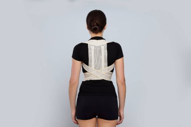 Woman with orthopedic corset on grey background, back view