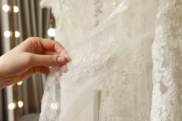 Young woman choosing wedding dress in salon, closeup