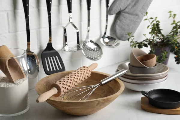 Different cooking utensils and plant on countertop in kitchen