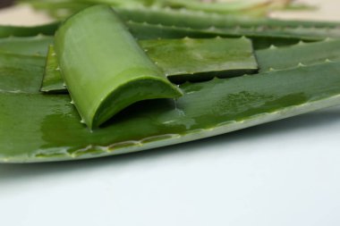 Taze kesilmiş sulu aloe vera yaprakları beyaz masada, yakın plan.
