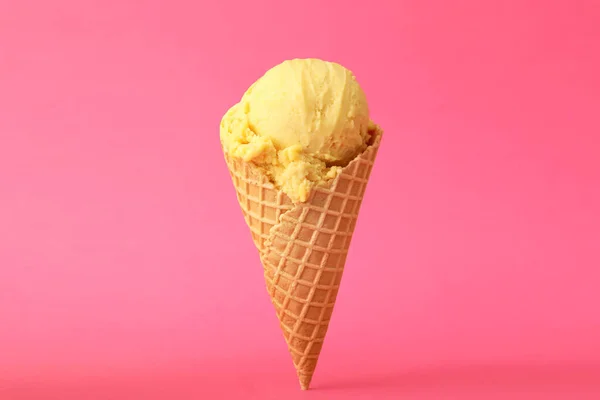 ピンクの背景にワッフルコーンのおいしい黄色のアイスクリーム — ストック写真
