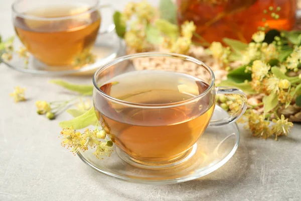 Tasty tea and linden blossom on light grey table