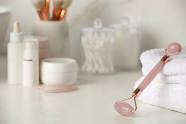 Natural face roller, gua sha tool and cosmetic products on counter in bathroom