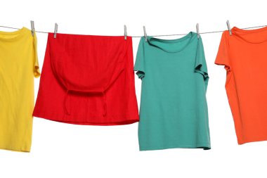 Different bright clothes drying on washing line against white background