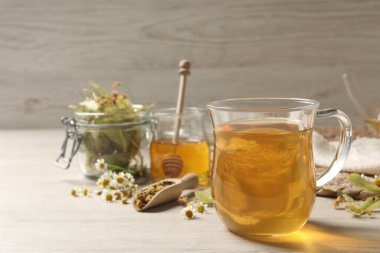 Taze demlenmiş çay ve beyaz ahşap masada kurutulmuş otlar. Metin için boşluk