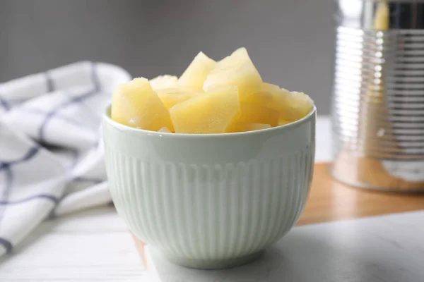 Pieces of canned pineapple in bowl on table, closeup