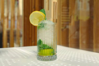 Glass of refreshing citrus drink on white table indoors