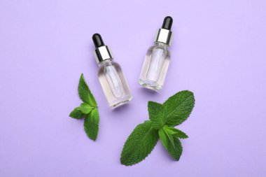Bottles of essential oil and mint on violet background, flat lay