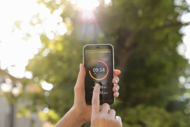 Genç bir kadın akıllı telefonunda spor uygulaması kullanıyor, yakın plan.