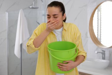 Banyoda kovası olan genç bir kadın bulantıdan muzdarip. Gıda zehirlenmesi