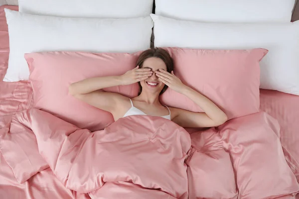 Jonge Vrouw Ontwaakt Comfortabel Bed Met Zijdezacht Linnengoed Bovenaanzicht — Stockfoto