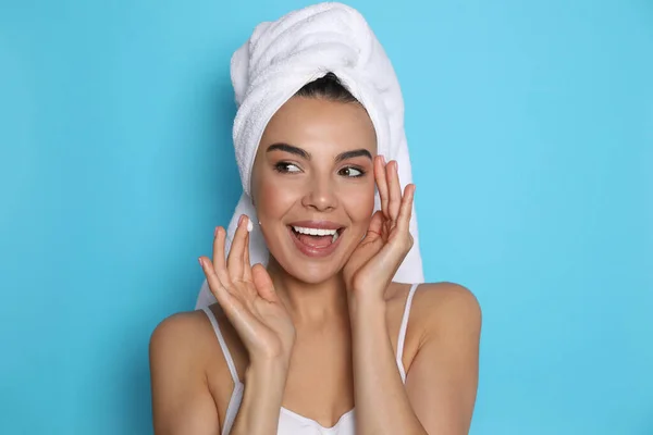 Beautiful Young Woman Towel Applying Cream Face Light Blue Background — Stock Photo, Image