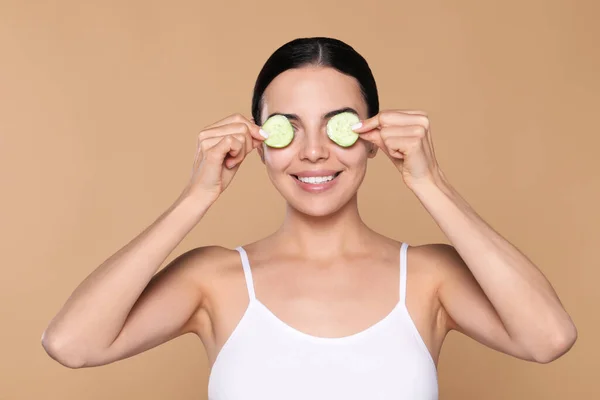 Beautiful Young Woman Putting Slices Cucumber Eyes Beige Background — Foto de Stock