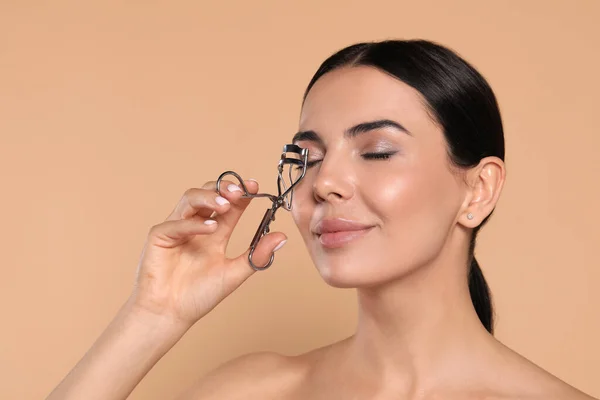 Beautiful Young Woman Using Eyelash Curler Beige Background — ストック写真