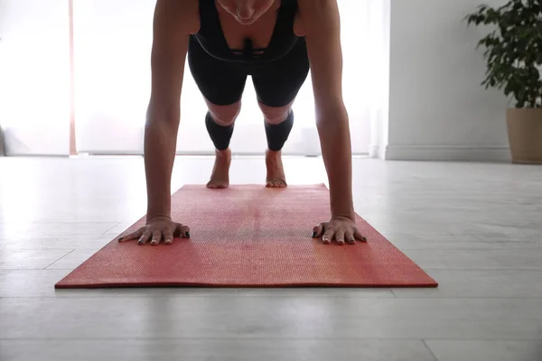 Woman practicing plank asana in yoga studio, closeup. Phalankasana pose