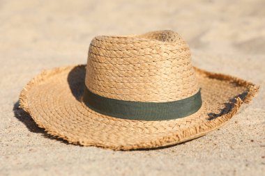 Straw hat on sandy beach. Stylish accessory