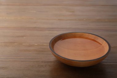 Bowl with clear water on wooden table. Space for text