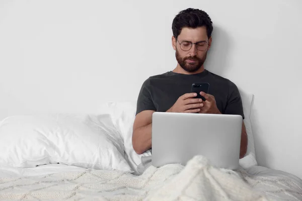 Handsome Man Using Smartphone Laptop Bed Space Text — Stockfoto