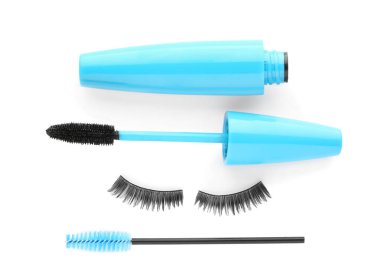 Fake eyelashes, curler and mascara on white background, top view