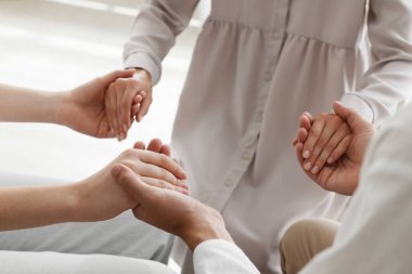 Bir grup dindar insan el ele tutuşup kapalı yerlerde dua ediyor.