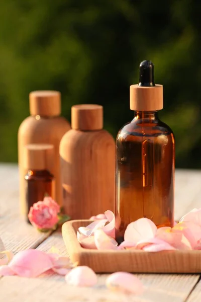 Bottles Rose Essential Oil Flowers White Wooden Table Outdoors Closeup — Stok fotoğraf