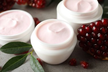 Doğal yüz maskesi, nar tohumları ve açık gri masada yeşil yapraklar, yakın plan.