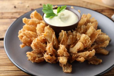 Ahşap masada servis edilen soslu kızarmış soğan, yakın plan.