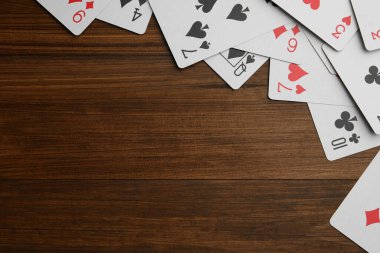 Playing cards on wooden table, flat lay. Space for text