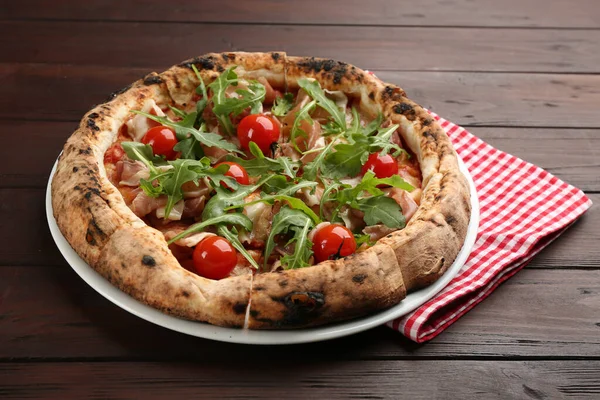 Tasty pizza with meat and arugula on wooden table