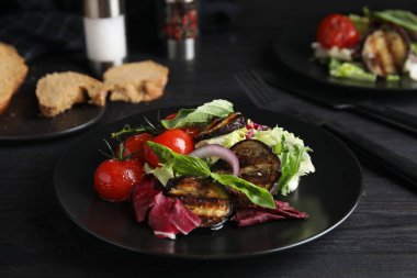 Kızarmış patlıcan ve siyah ahşap masada servis edilen fesleğenli lezzetli salata.