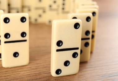 White domino tiles with black pips on wooden table, closeup