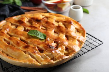 Fresh traditional apple pie with mint on light grey table, closeup